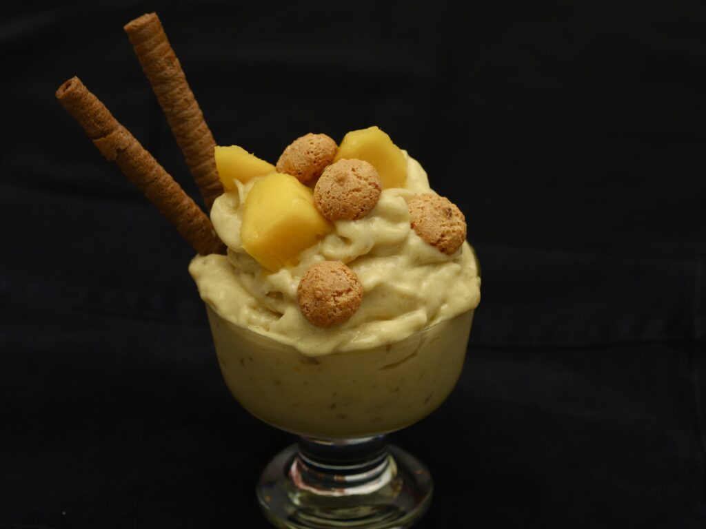 coppa di gelato al mango guarnita con amaretti, cialde e mango fresco
